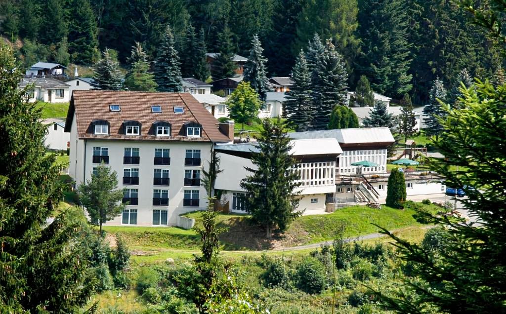 um grande edifício branco numa colina com árvores em Waldhotel Feldbachtal em Neuhaus am Rennweg