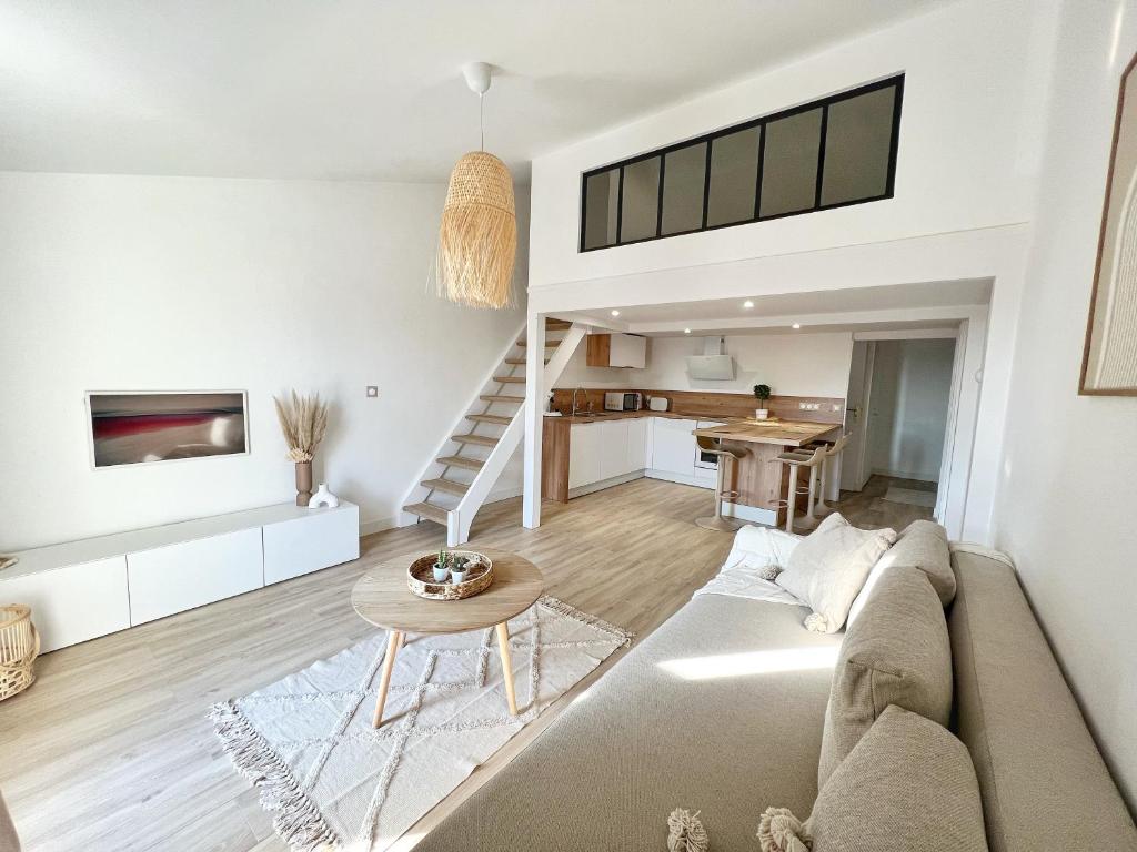 ein Wohnzimmer mit einem Sofa und einem Tisch in der Unterkunft Le Petit Bohème - Cocon Rochelais in La Rochelle
