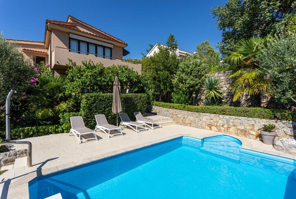 a swimming pool with two chairs and an umbrella at Apartments House Barbara in Kornić