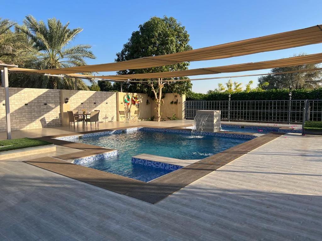 a swimming pool in a patio with an umbrella at Al Khamail Land for Greenhostel in Al Wāşil