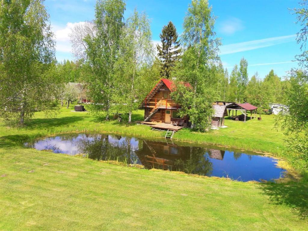 une cabane en rondins dans un champ à côté d'un étang dans l'établissement Saunamaja, à Myza Kastre