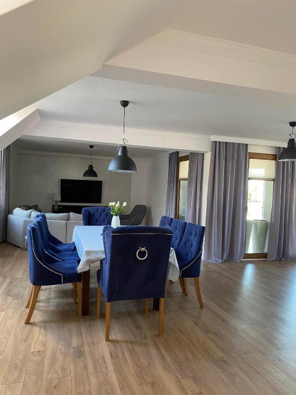 a dining room with blue chairs and a table at Apartament DeLux in Pasłęk