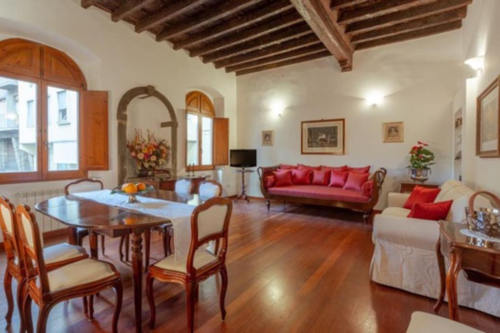 un salon avec une table et un canapé rouge dans l'établissement Ponte Vecchio - Appartamento Oltrarno Ruby, à Florence