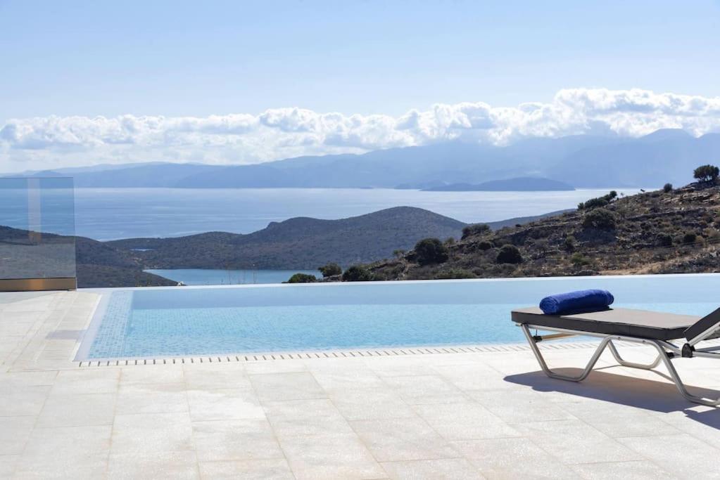 a bench next to a pool with a view of the mountains at Falcon Villa in Chavgas