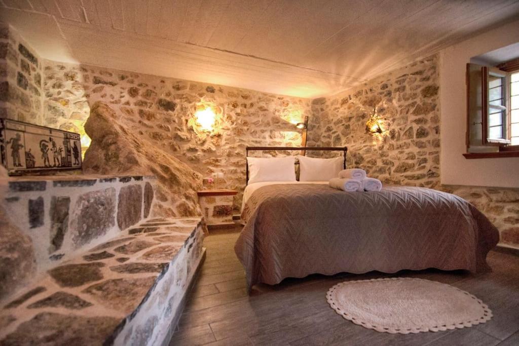 ein Schlafzimmer mit einem Bett in einer Steinmauer in der Unterkunft Braxos A beautiful rocky place in Hydra