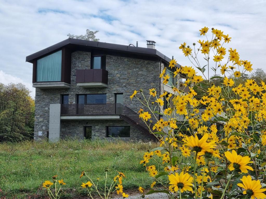 una casa en la cima de una colina con flores amarillas en Agriturismo B&B Caffè e Vino, en Sondrio
