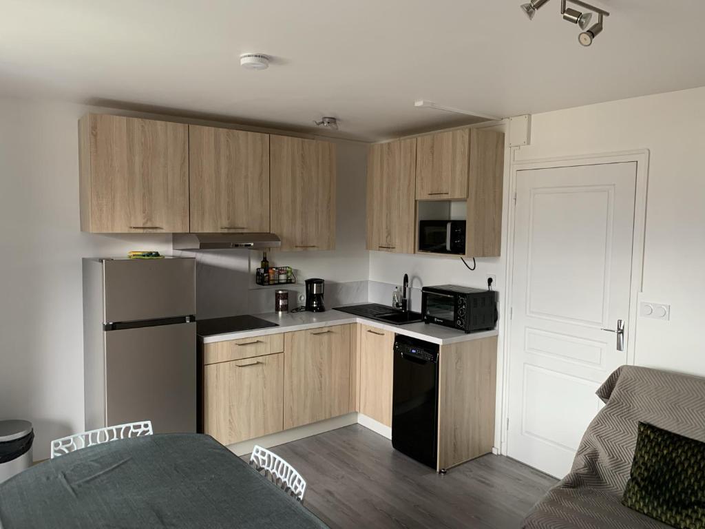 uma cozinha com armários de madeira e um frigorífico preto em Appartement agréable à deux pas du plan d'eau em Embrun