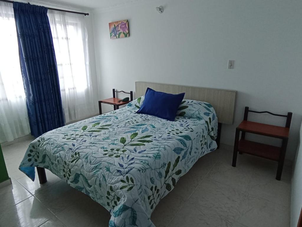 a bedroom with a bed with a blue pillow and a chair at Diamante Blue Hotel in Villavicencio