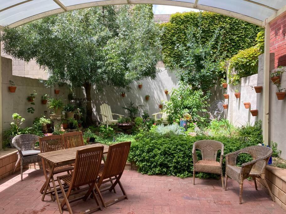 a patio with a table and chairs in a garden at Carolyn's Cottage in Adelaide
