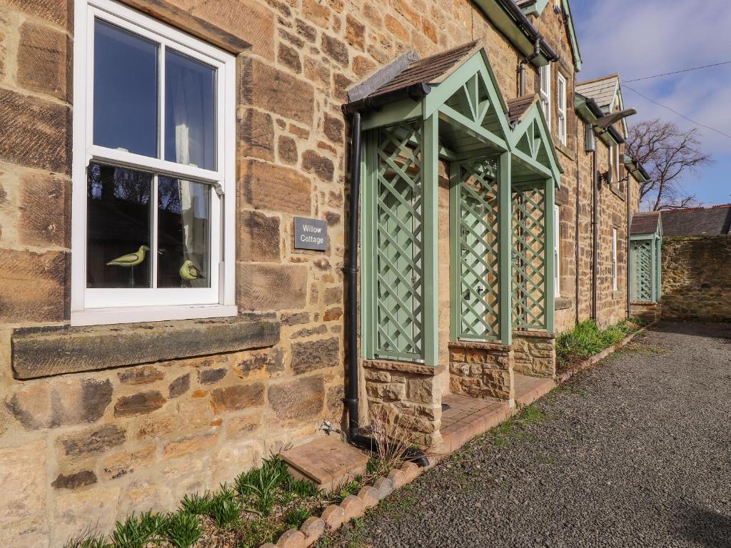 a brick building with a green door and a window at Willow Cottage in Alnmouth