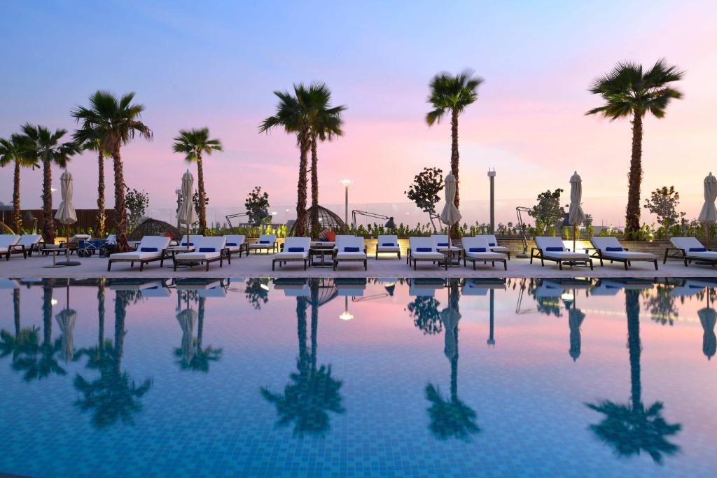 una piscina con sillas y palmeras en InterContinental Residences Abu Dhabi, an IHG Hotel, en Abu Dabi