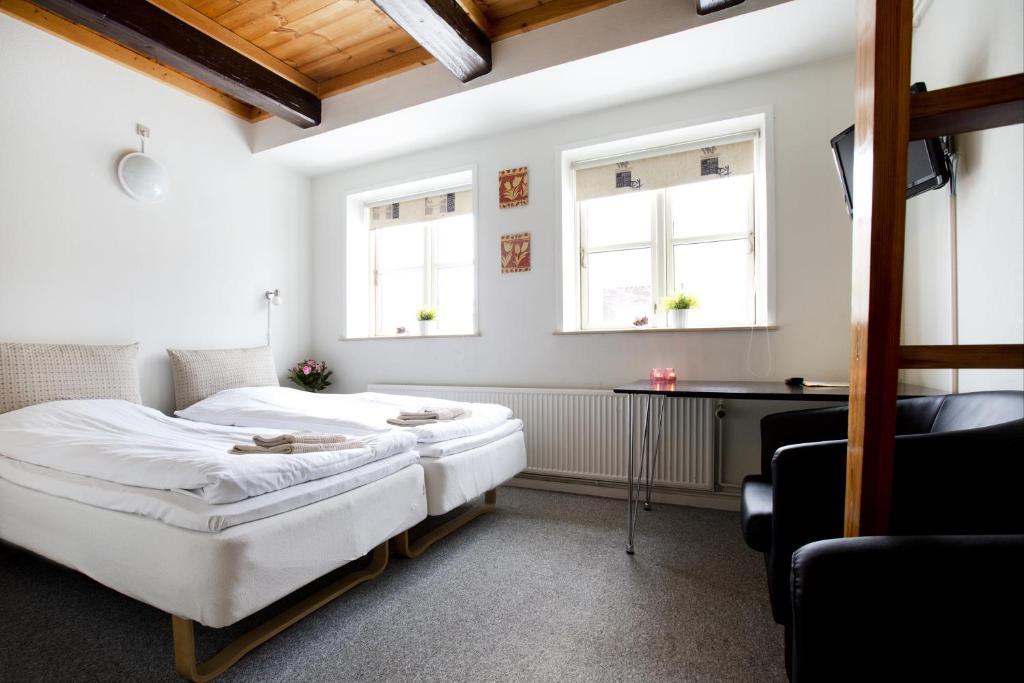 2 Betten in einem Zimmer mit einem Schreibtisch und Fenstern in der Unterkunft Motel Stege in Stege