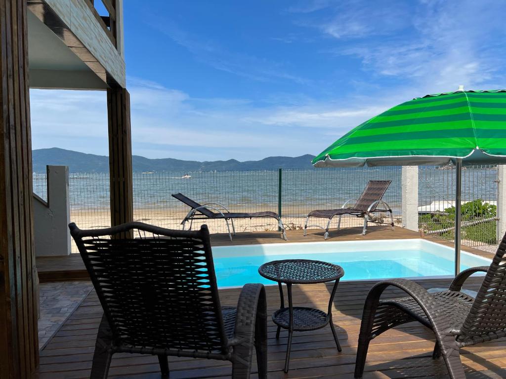 un patio con sillas, una piscina y una sombrilla en Recanto Pé na Areia SC en Palhoça