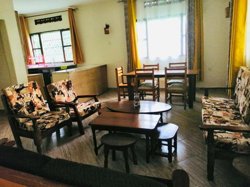 a living room with chairs and tables and a dining room at Home from home in Mbale