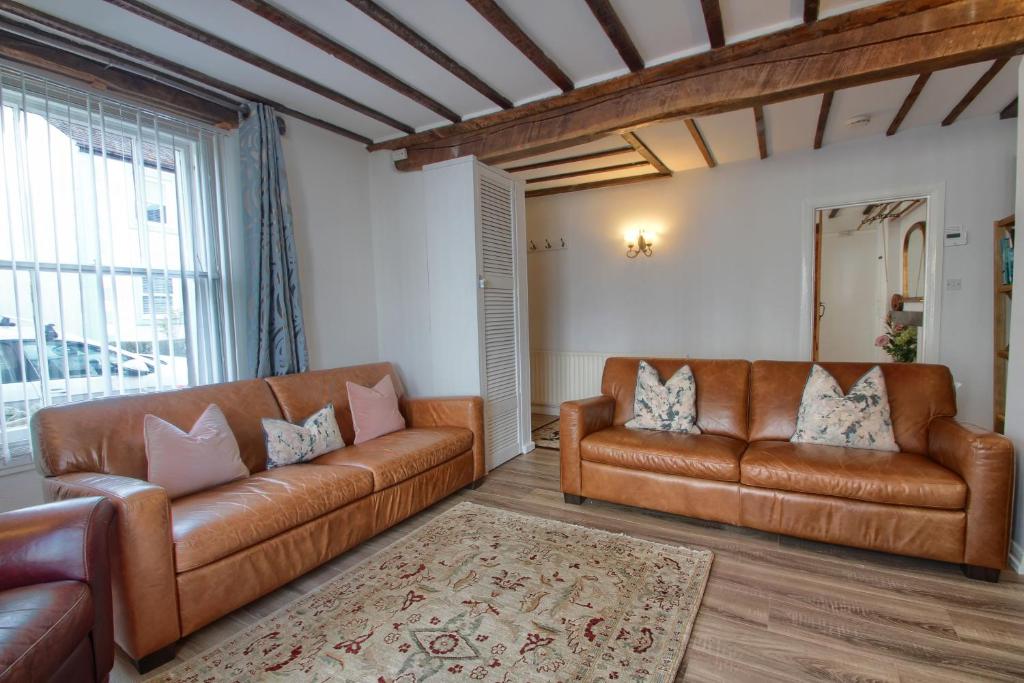 a living room with two leather couches and a rug at Acorn Cottage in Keswick