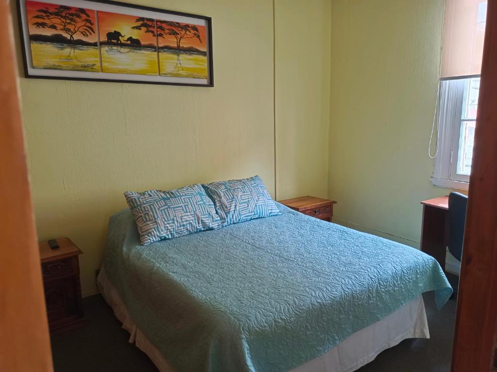 a bedroom with a bed with a blue comforter at Hotel Paseo Valle in Viña del Mar