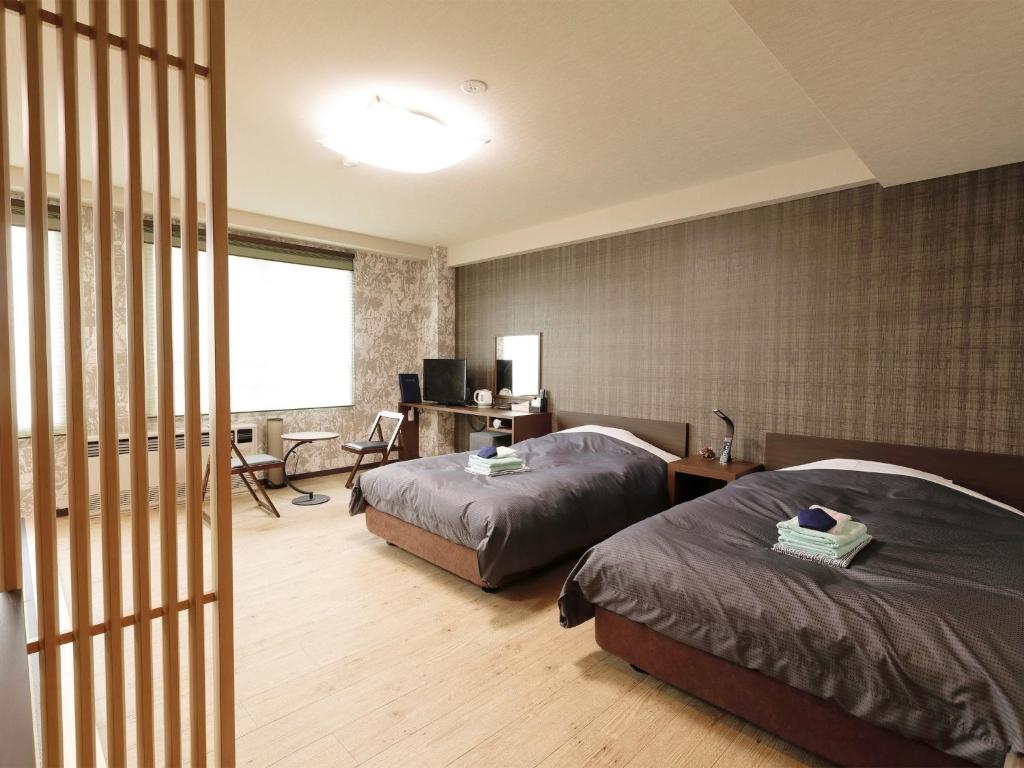 Apprising hotels GranJam Tsugaike - Vacation STAY 77381v في Chikuni: غرفة نوم بسريرين ومكتب فيه كمبيوتر