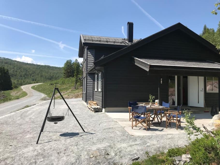 a black house with a table and chairs in front of it at Grand and modern cabin in Sogndal