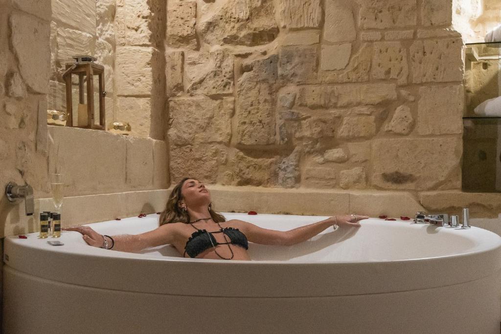 a woman laying in a bath tub in a bathroom at Le Nicchie luxury rooms in Lecce