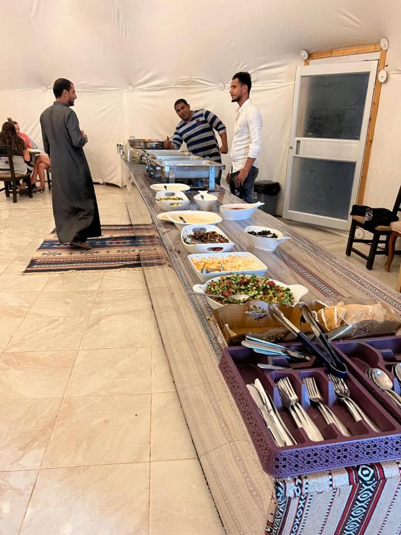 a group of men standing around a table with food at Wadi Rum Oscar camp in Wadi Rum