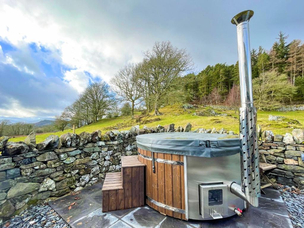 a hot tub sitting next to a stone wall at Coed Mawr in Betws-y-coed