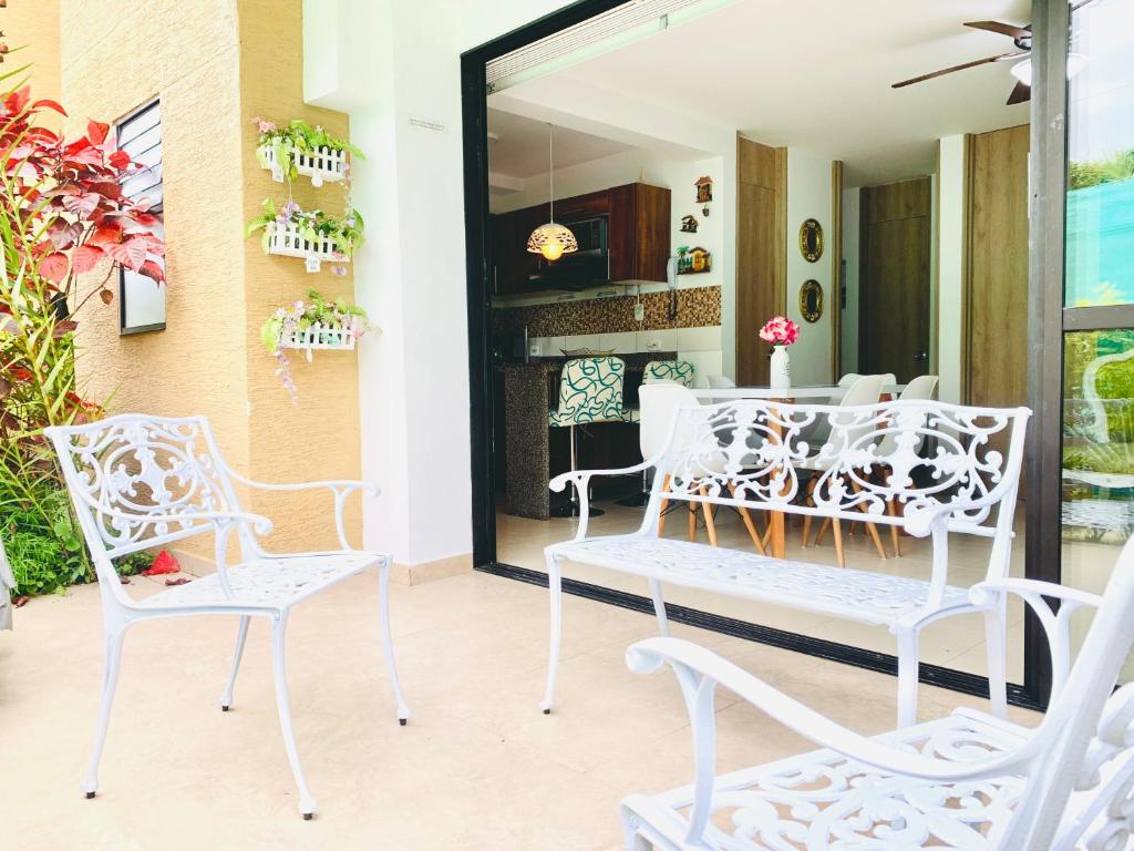 eine Veranda mit 2 weißen Stühlen und einem Tisch in der Unterkunft Apartamento en el Eje Cafetero Quindio con piscina jacuzzi wifi in La Tebaida