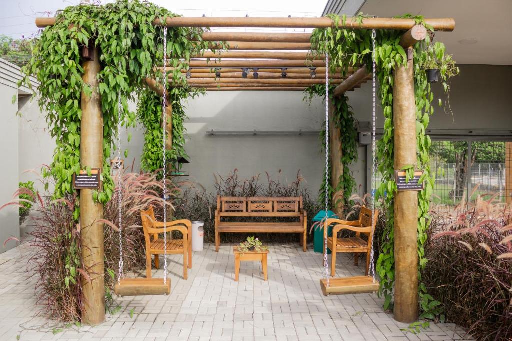 a wooden pergola with chairs and a table at Hotel e Pousada Bem Bom - Itu in Itu