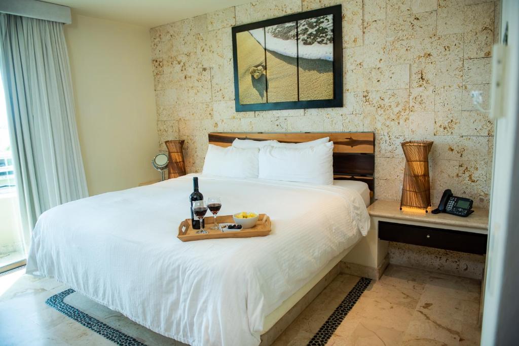 a hotel room with a bed with a tray of food on it at El Taj Oceanfront and Beachside Condo Hotel in Playa del Carmen