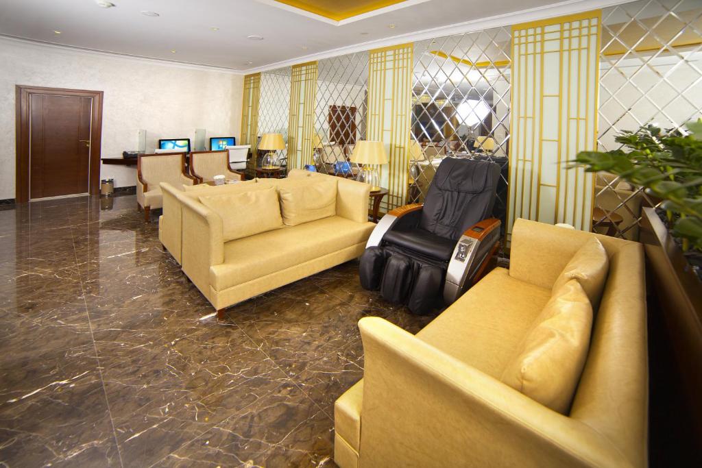 a living room with yellow couches and a desk at Raviz Center Point Hotel in Dubai