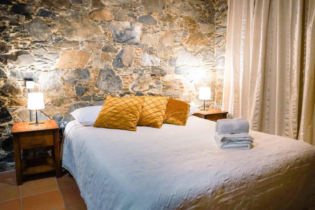 a bedroom with a bed with two lamps and a stone wall at Archontiko Rousias in Nicosia