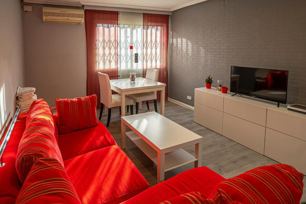 uma sala de estar com um sofá vermelho e uma mesa em Bonito, Práctico y muy bien comunicado em Madri