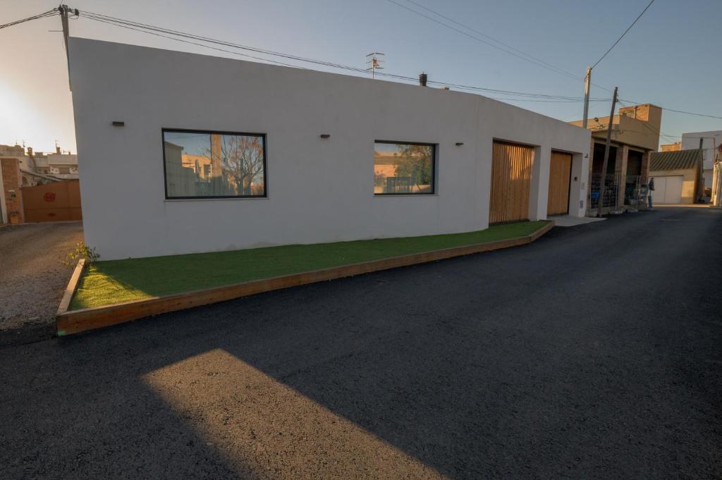 un edificio bianco con un prato verde sul lato di Casa Casver a Deltebre