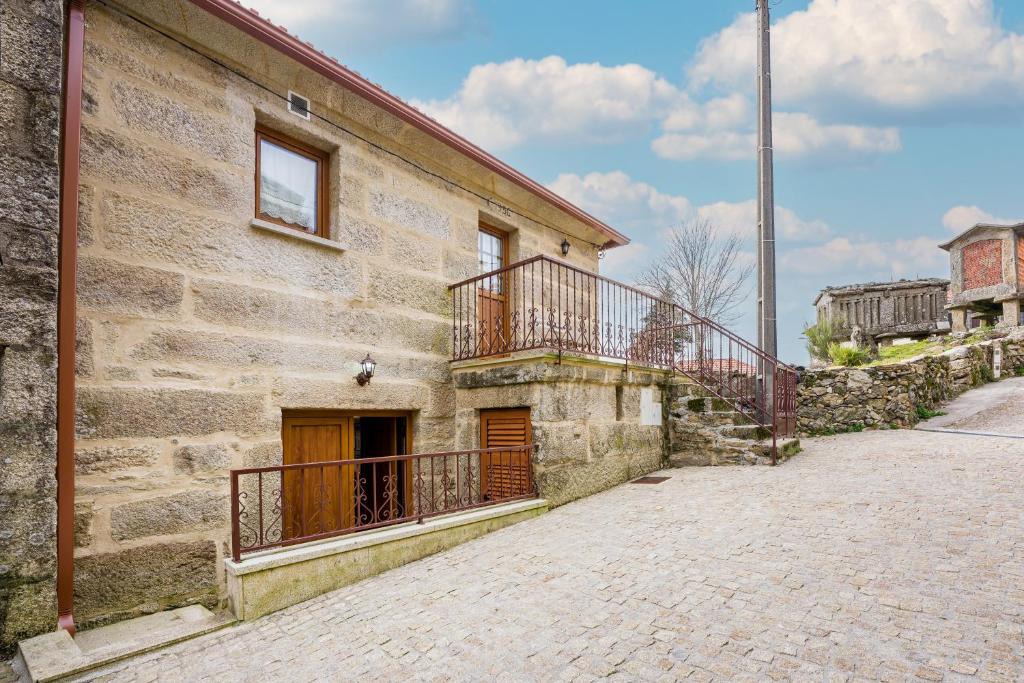 - un vieux bâtiment en pierre avec un balcon dans une rue dans l'établissement Casa do Rego, à Melgaço