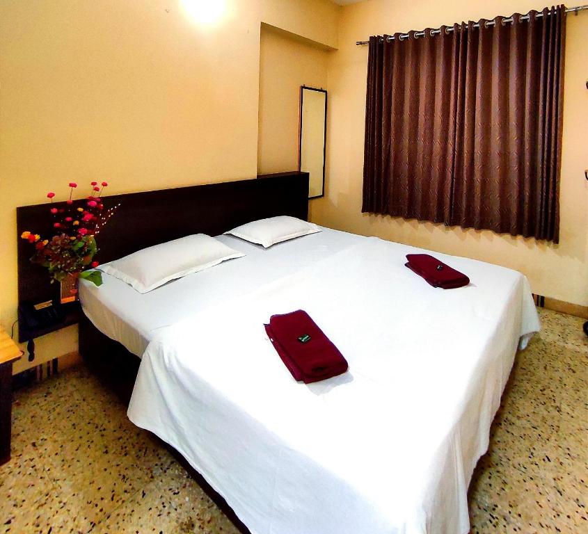 a bedroom with a large white bed with two red towels on it at Mandarin Hotel Mapusa in Mapusa