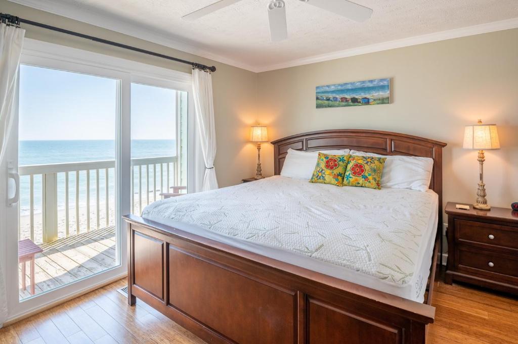 1 dormitorio con 1 cama y balcón con vistas al océano en Ocean Dunes 1701 Seas The Day, en Kure Beach