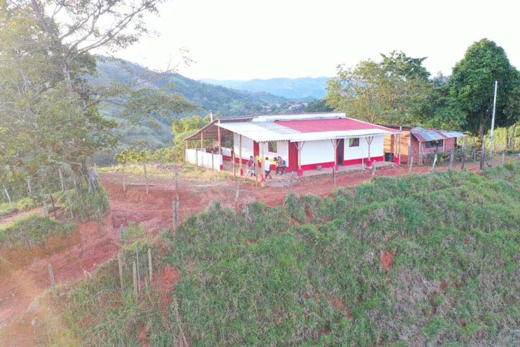 een huis met een rood dak in een veld bij Ecohotel Casa de Descanso La Pradera in Confines