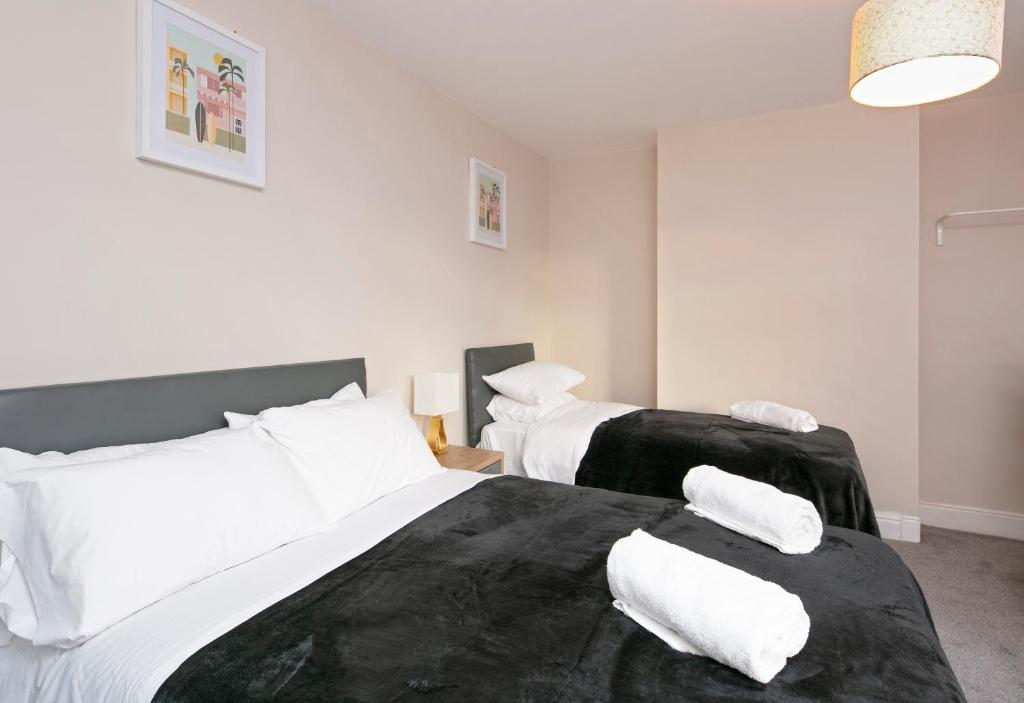 a bedroom with two beds with black and white sheets at SPS Homes in Birmingham