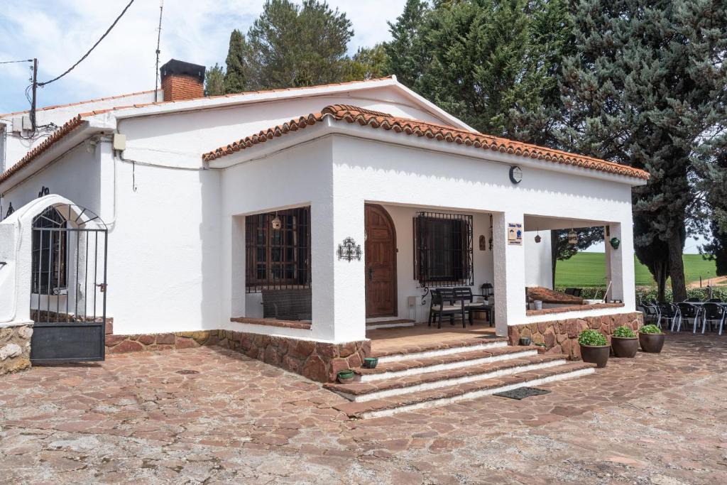 a small white house with a porch and stairs at Dehesa Vieja Casa Rural in Alarcón