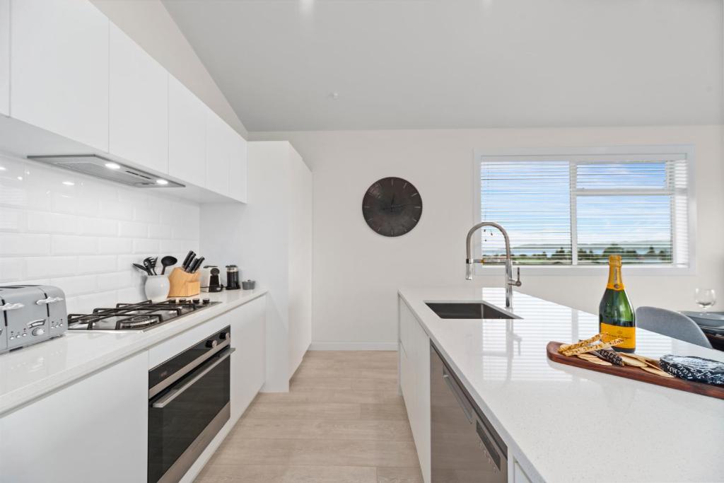 een witte keuken met witte werkbladen en een wastafel bij Timeout @ Taupo - Lake Views in Taupo
