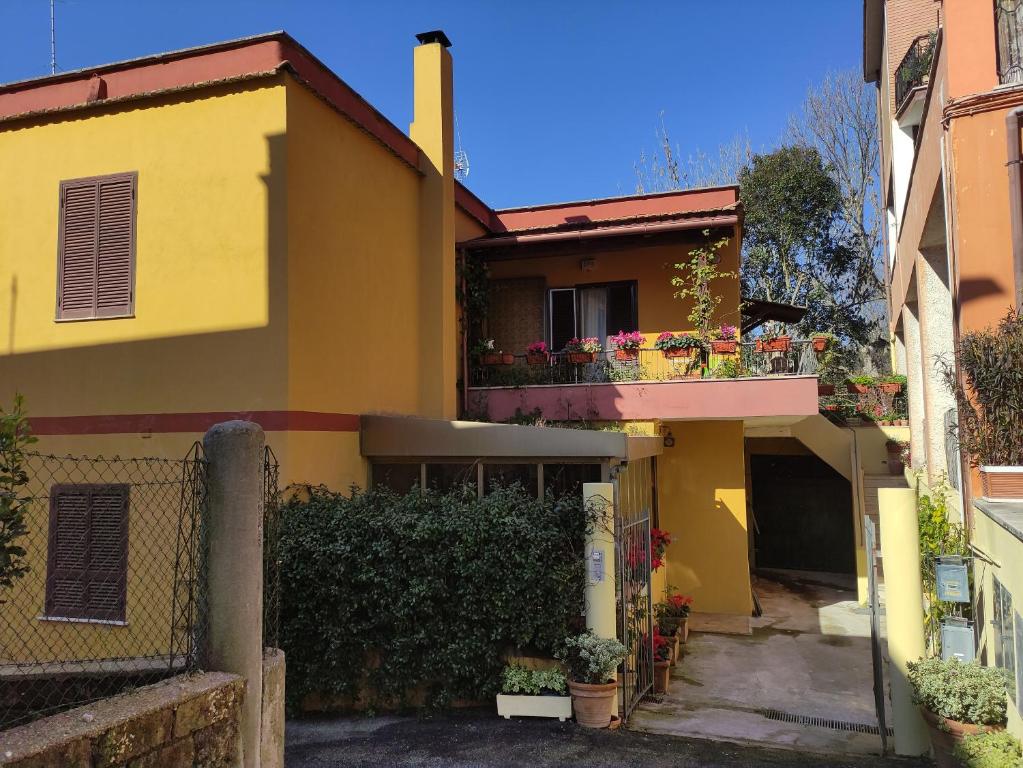 a yellow house with a balcony with flowers at Elisa e Carla House Beautiful apartments on the Cassia in Rome