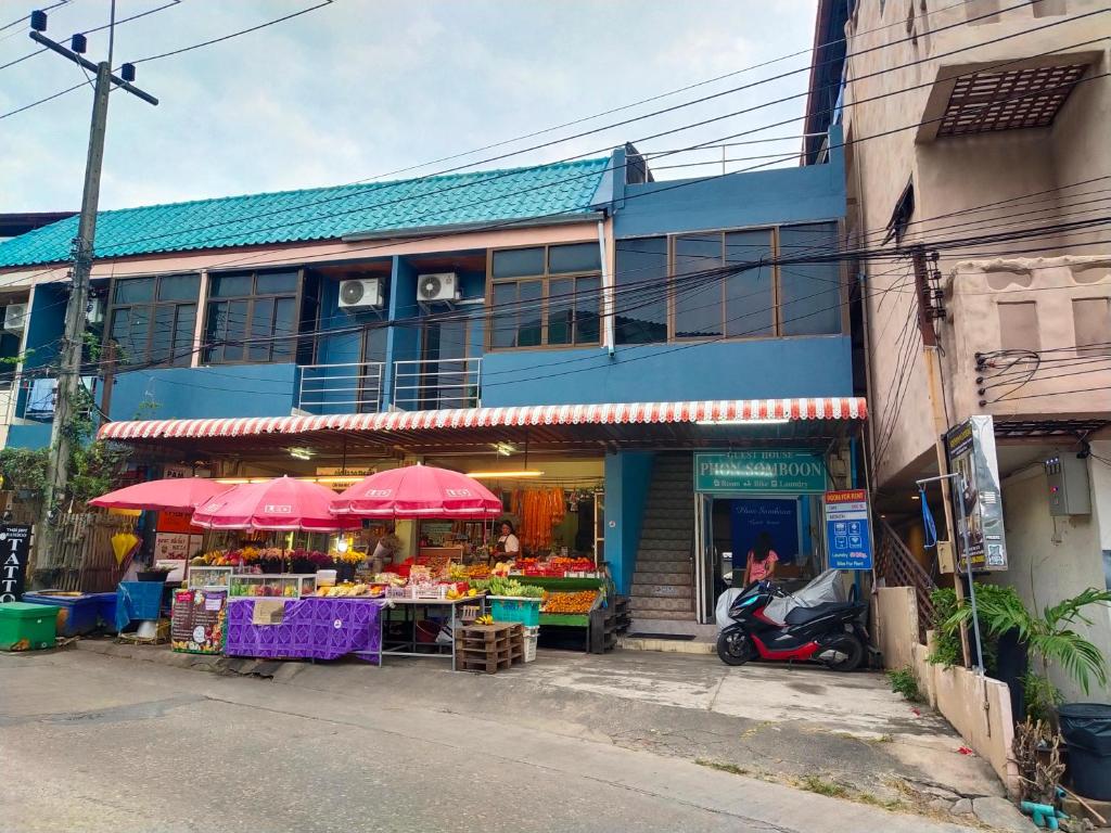 a fruit stand with pink umbrellas in front of a building at Phonsomboon Guesthouse in Koh Tao