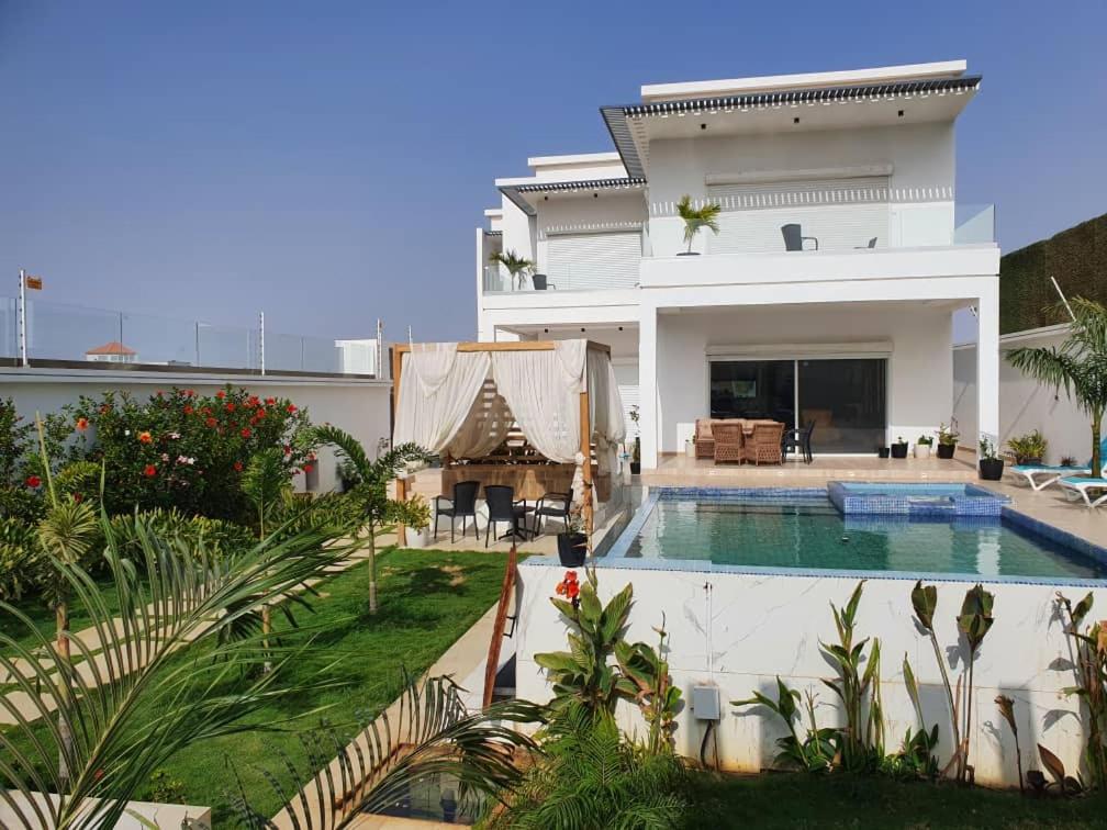 a villa with a swimming pool in front of a house at Diamond House in Saly Portudal