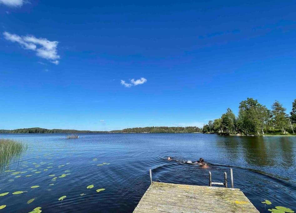 a person swimming on a dock on a lake at Stort hus med trädgård - sjötomt med egen båt 
