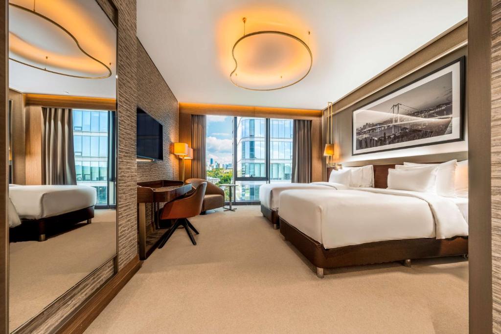 a hotel room with two beds and a desk at Radisson Collection Hotel, Vadistanbul in Istanbul