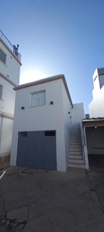 a white building with a garage and a staircase at Balcones del Cerro Mono ambiente céntrico 2p - camas simples in Villa Carlos Paz