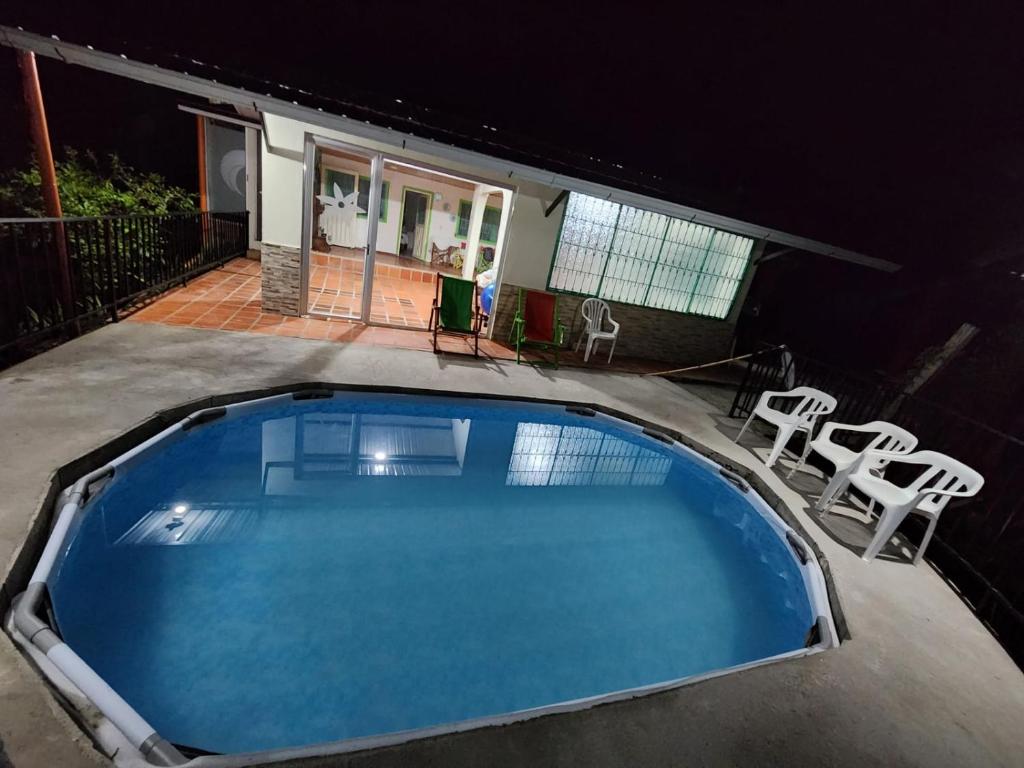 een groot zwembad met stoelen en een huis bij CASA DE CAMPO CORRALEJAS - ANOLAIMA in Anolaima