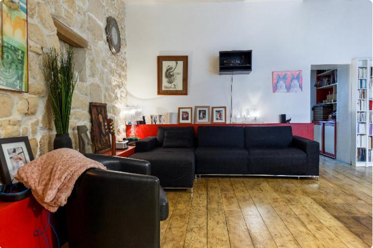 a living room with a black couch and a stone wall at Appartement Panthéon in Paris
