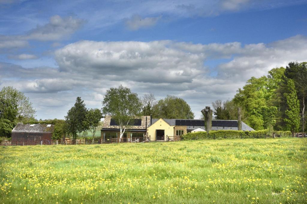 een huis in een veld met een grasveld bij The Stables and The Tackroom at Castle Chase, Ayston 