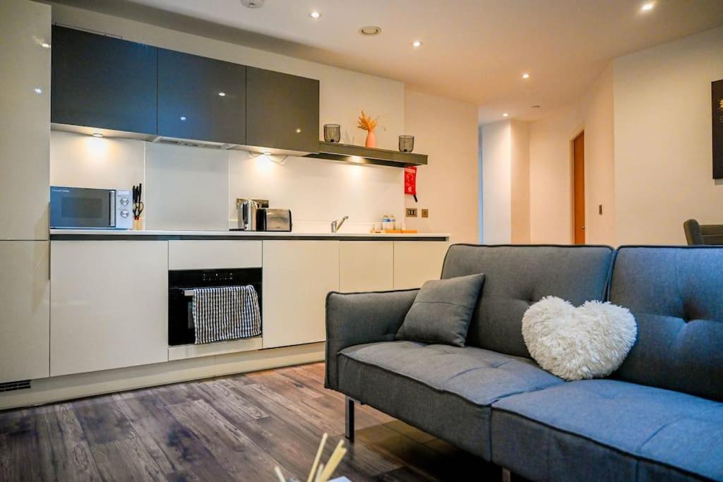 a living room with a blue couch and a kitchen at Luxury 2 bedroom apartment in Birmingham