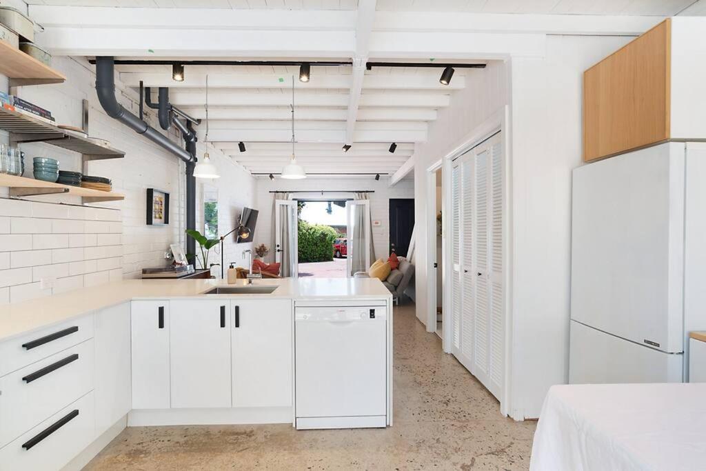 a kitchen with white cabinets and white walls at Stylish, comfortable and pet friendly home in the heart of Kensington in Norwood
